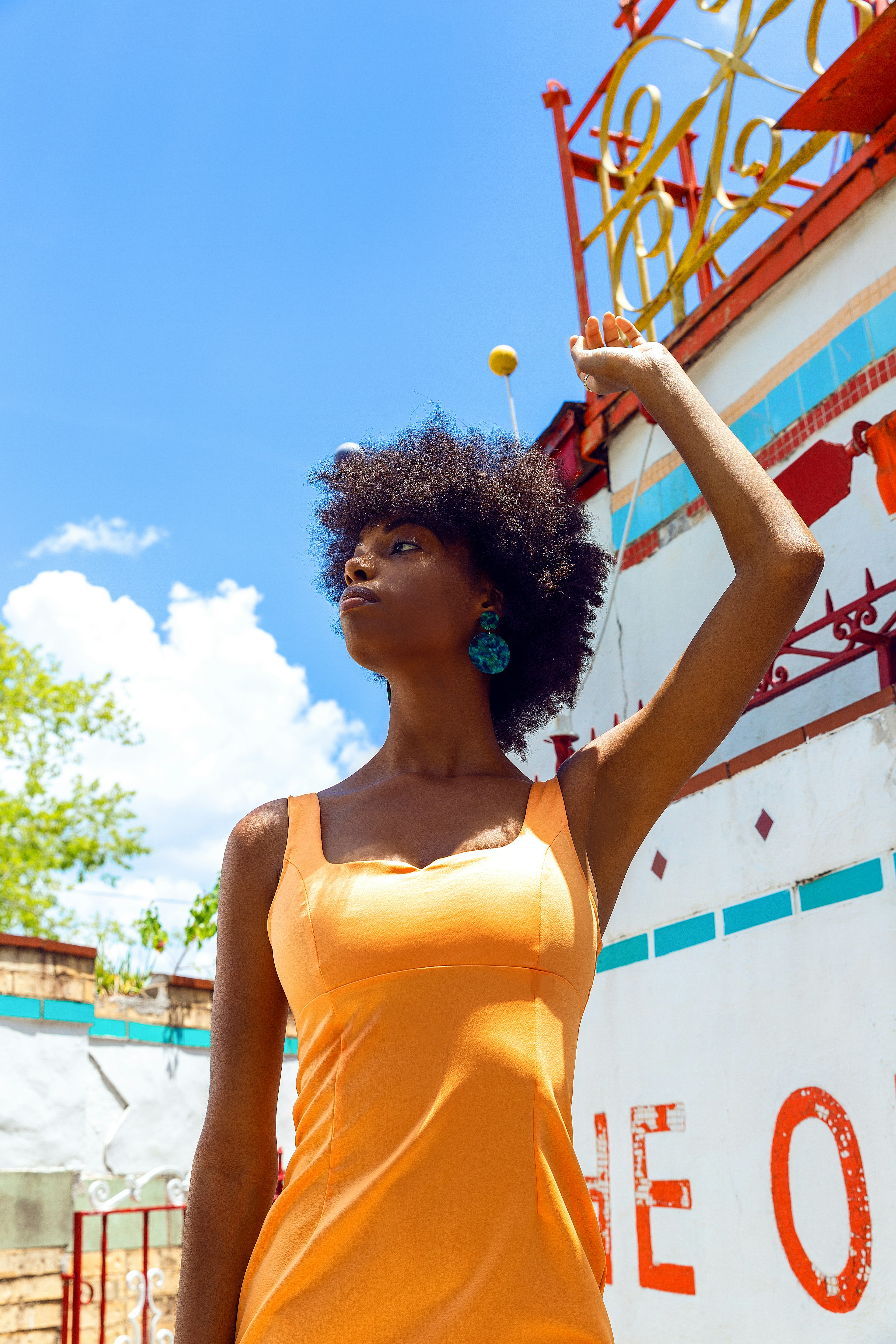 woman in yellow tank top standing near white and red wall during daytime